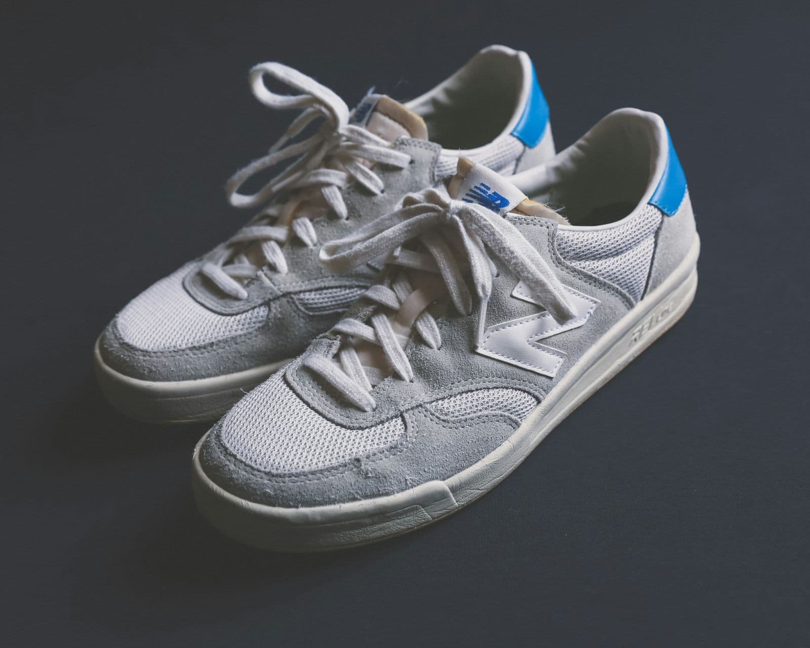 Pair of grey New Balance sneakers on a dark surface